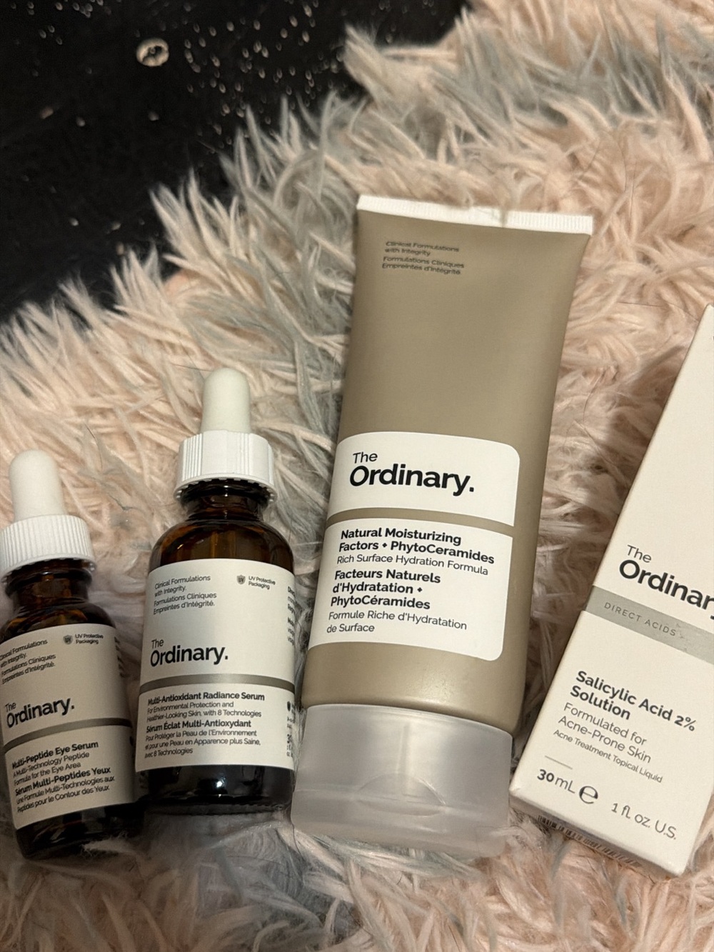 The Ordinary skincare trio in cream, white, and amber tones